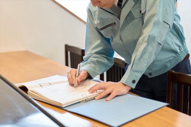 現場でクリップボードに調査結果を記録する、アスベスト事前調査の作業風景